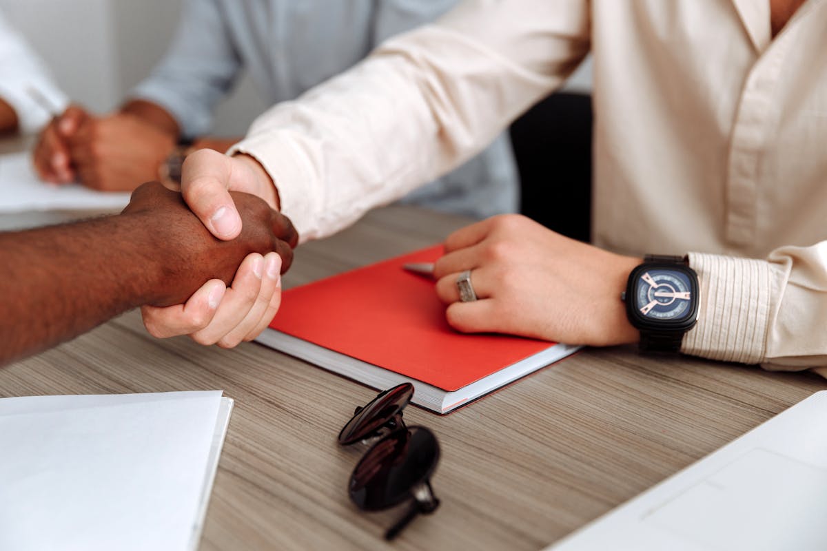 Business partners shaking hands over planning documents